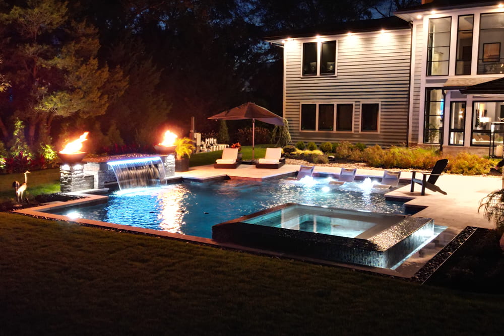 geometric pool with spillover spa at night