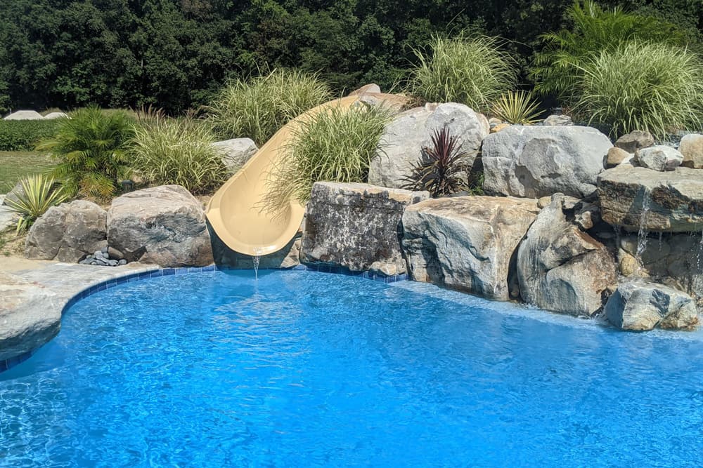 freeform pool with slide and boulder waterfall