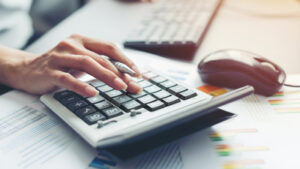 business woman hand using calculator near loan paperwork and keyboard