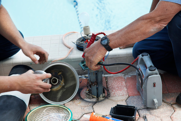 two technicians repairing swimming pool equipment